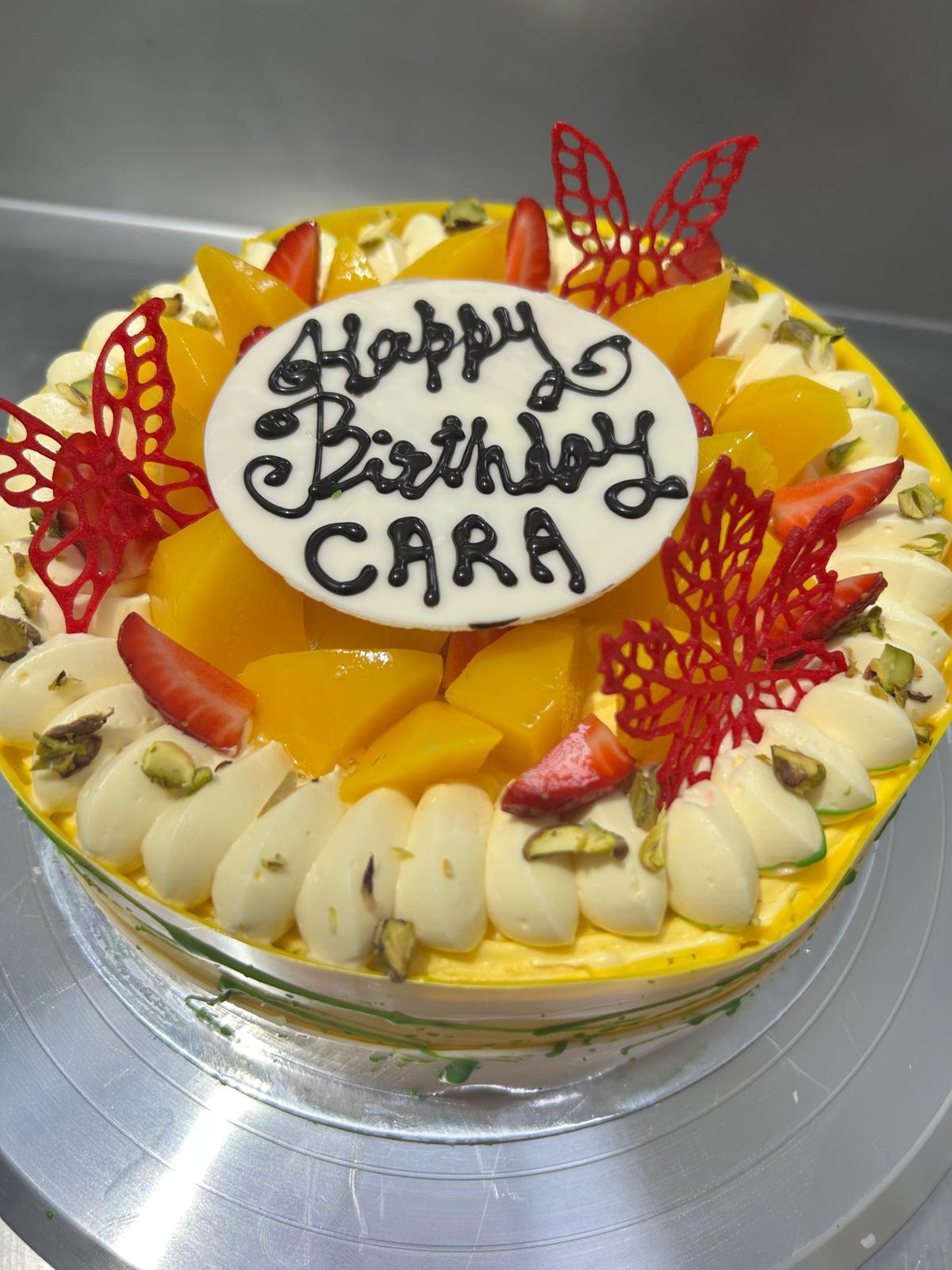 Mango birthday cake with strawberries pistachios and butterfly decorations