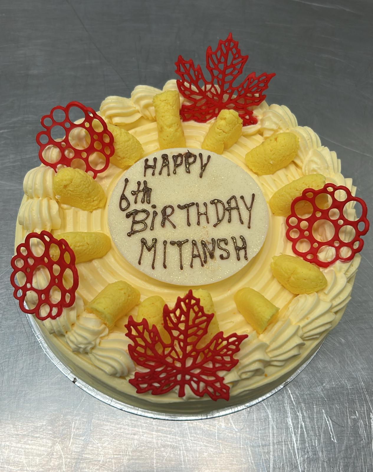 Mango birthday cake with red lace leaves and cream piping