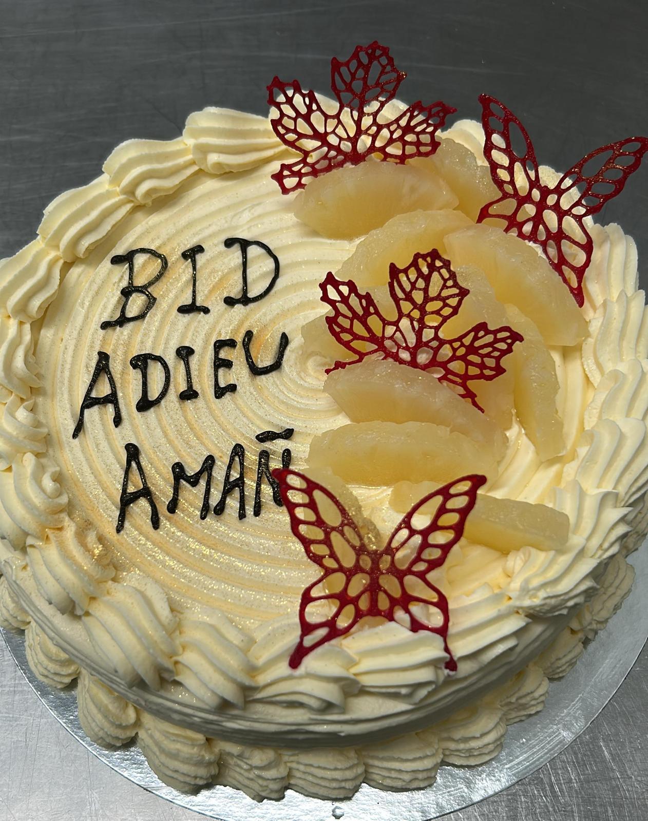 Pineapple farewell cake with piped cream and red butterfly decorations